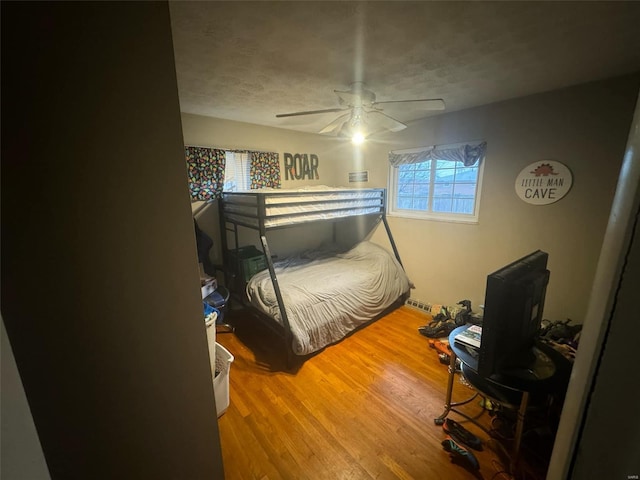 bedroom with wood-type flooring, a textured ceiling, and ceiling fan