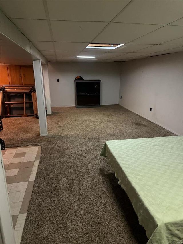 basement with a paneled ceiling and carpet flooring