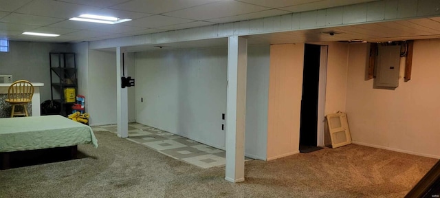 basement featuring a paneled ceiling, light carpet, and electric panel