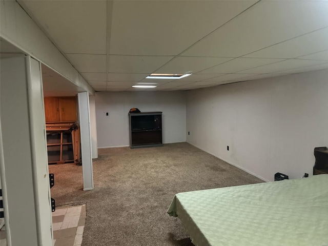 basement with a paneled ceiling and carpet floors