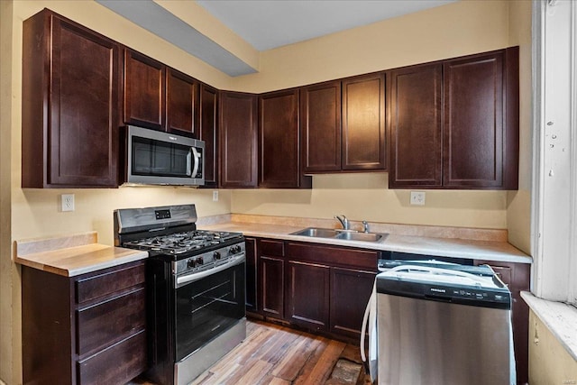 kitchen featuring sink, dark brown cabinets, light hardwood / wood-style floors, and appliances with stainless steel finishes