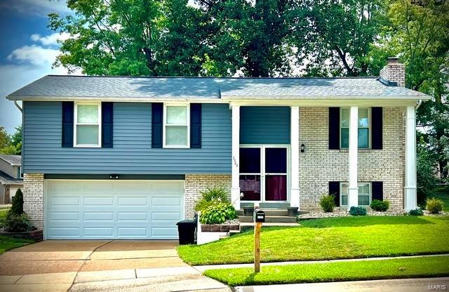 bi-level home featuring a garage and a front lawn