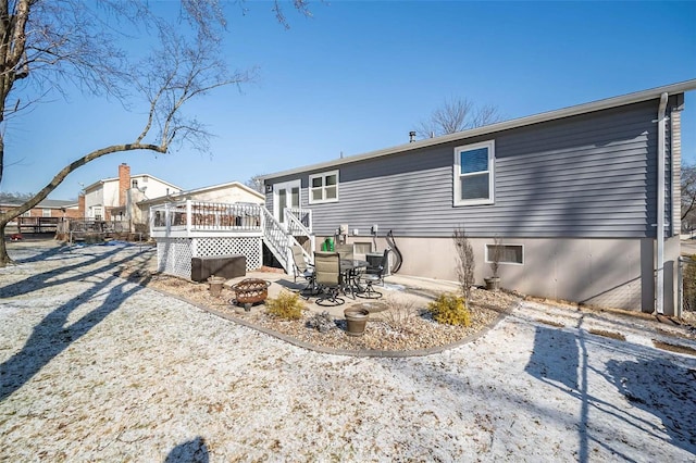 back of property with a wooden deck and a fire pit