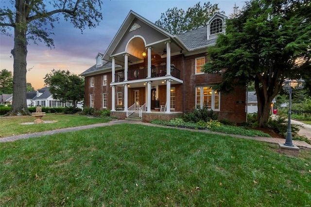 view of front of house with a balcony and a lawn