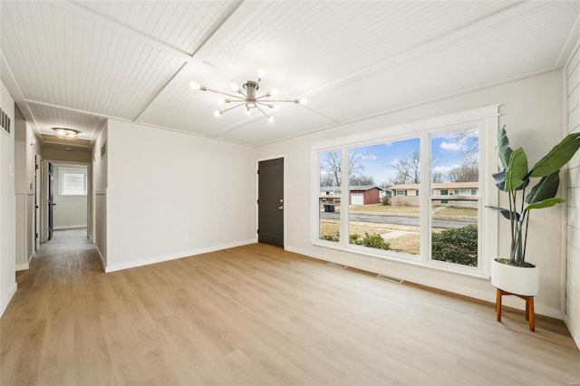 empty room with light hardwood / wood-style flooring and a notable chandelier