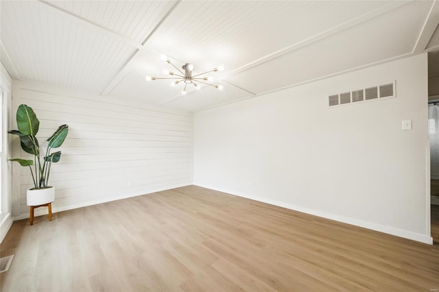 spare room with hardwood / wood-style flooring and a notable chandelier