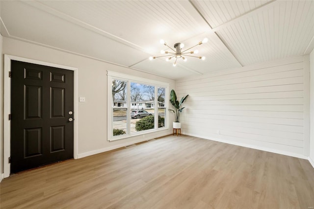 foyer with wood walls, a notable chandelier, wooden ceiling, beam ceiling, and light hardwood / wood-style flooring