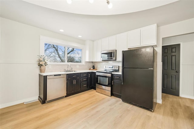 kitchen with stainless steel appliances, light hardwood / wood-style floors, sink, and white cabinets