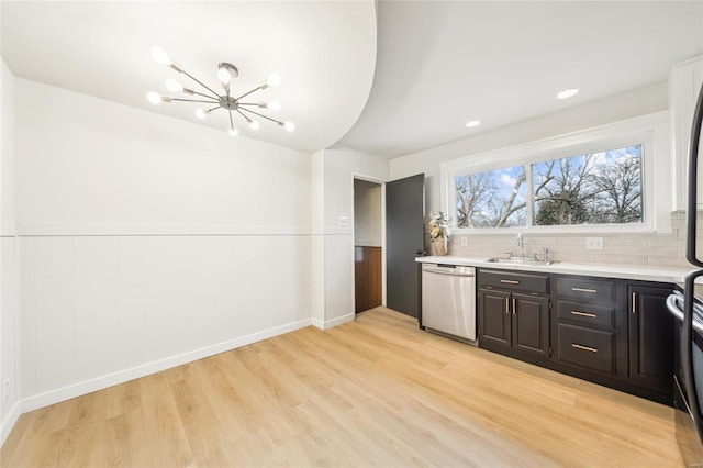 kitchen featuring sink, an inviting chandelier, light hardwood / wood-style flooring, dishwasher, and decorative backsplash