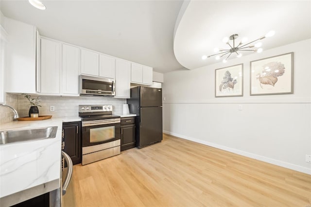 kitchen with sink, white cabinets, stainless steel appliances, light stone countertops, and backsplash