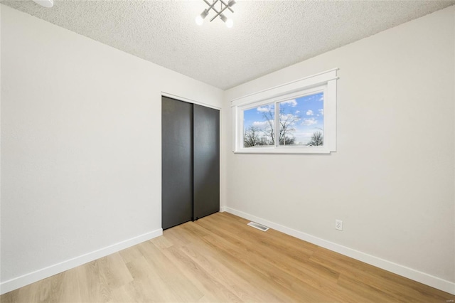 unfurnished bedroom with a closet, light hardwood / wood-style flooring, and a textured ceiling