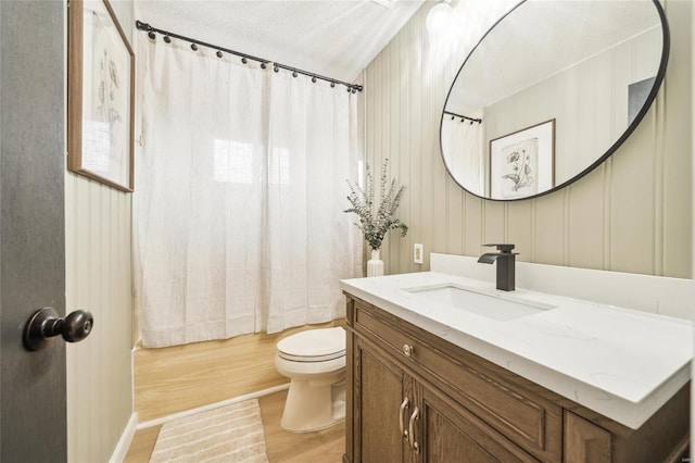 full bathroom featuring hardwood / wood-style flooring, vanity, toilet, shower / bathtub combination with curtain, and a textured ceiling