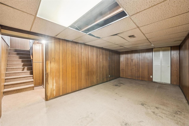 basement with wooden walls and a drop ceiling