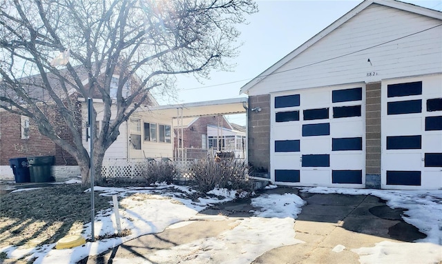 snow covered property with a garage and an outdoor structure