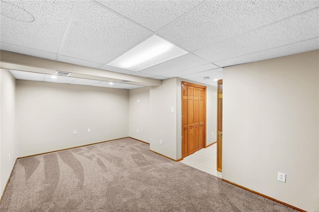 basement featuring light colored carpet and a paneled ceiling