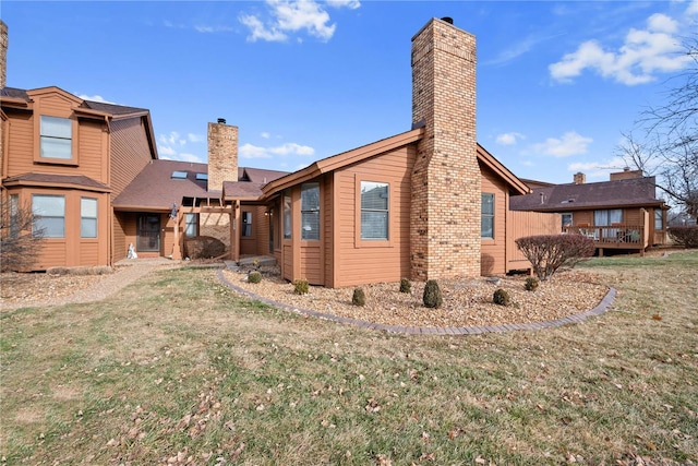 rear view of property featuring a wooden deck and a lawn