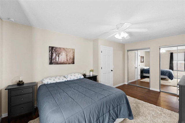 bedroom featuring dark wood-type flooring, ceiling fan, and two closets