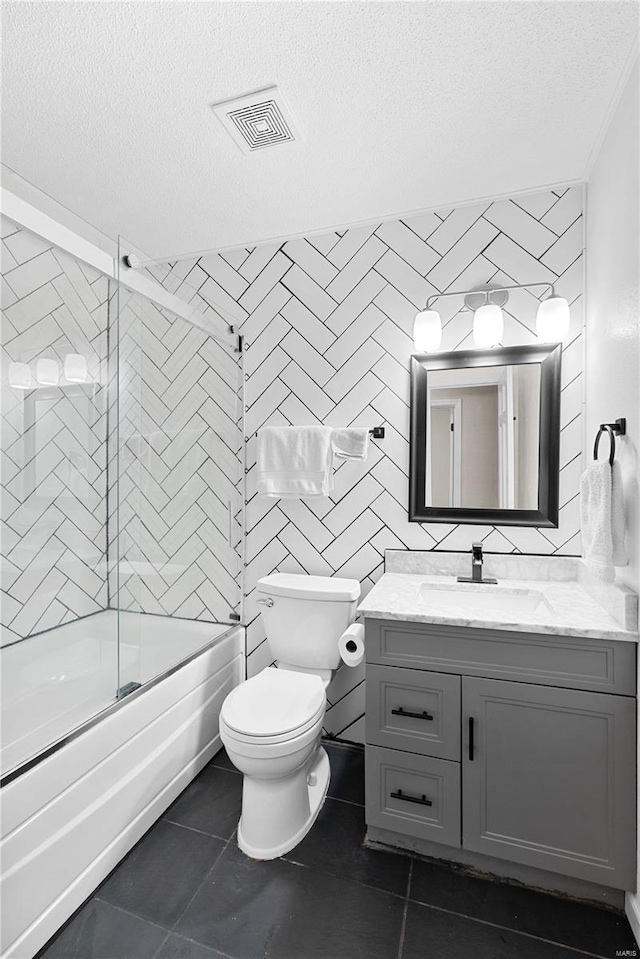 full bathroom with vanity, tile patterned floors, shower / bath combination with glass door, and a textured ceiling