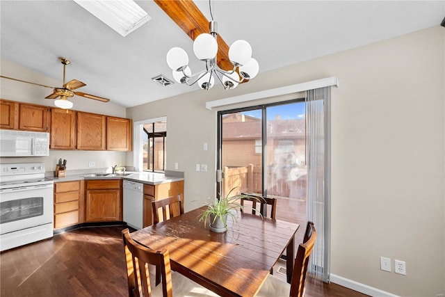 kitchen featuring sink, dark hardwood / wood-style floors, pendant lighting, white appliances, and vaulted ceiling with skylight