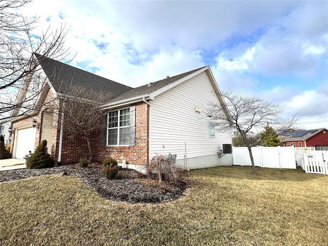 view of side of property with a garage, a yard, and central AC unit