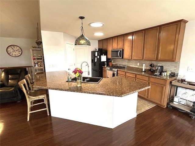 kitchen with appliances with stainless steel finishes, decorative light fixtures, sink, a breakfast bar area, and dark hardwood / wood-style flooring