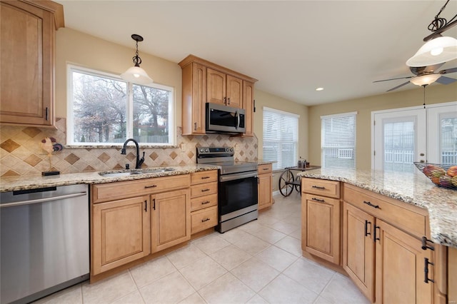 kitchen with appliances with stainless steel finishes, pendant lighting, tasteful backsplash, sink, and light stone countertops