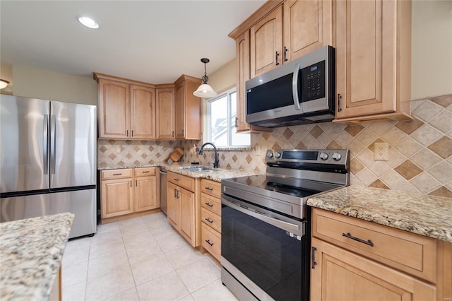 kitchen featuring appliances with stainless steel finishes, sink, light stone counters, and decorative light fixtures