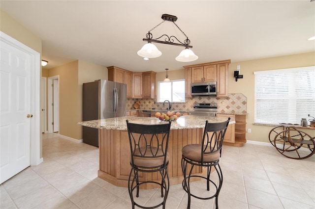 kitchen with light stone counters, appliances with stainless steel finishes, a center island, and tasteful backsplash