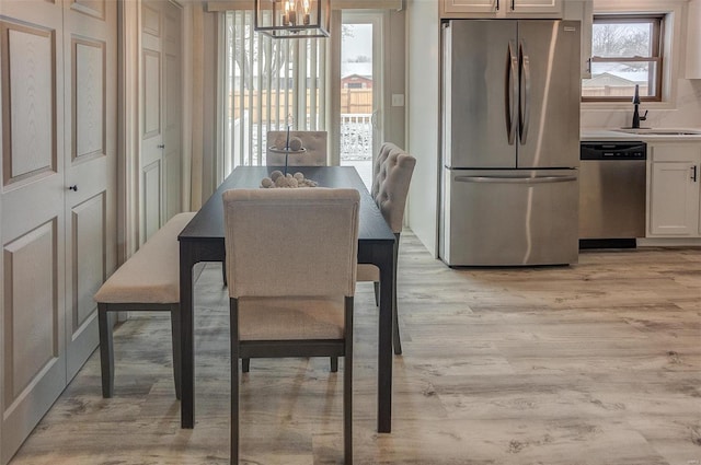 dining space featuring sink, a notable chandelier, and light wood-type flooring