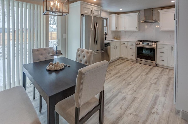 dining space with sink, decorative light fixtures, light wood-type flooring, and white cabinets