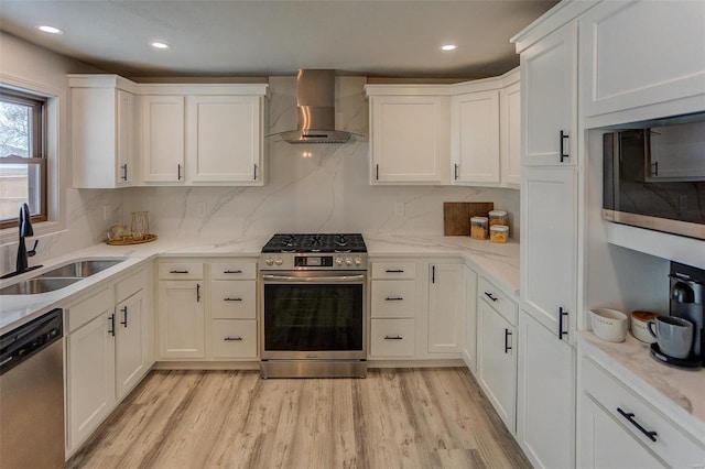 kitchen with white cabinetry, wall chimney range hood, sink, and appliances with stainless steel finishes