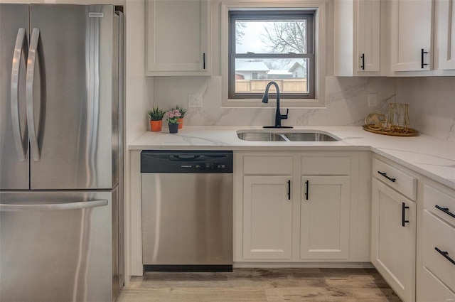 kitchen featuring white cabinetry, stainless steel appliances, light stone countertops, and sink