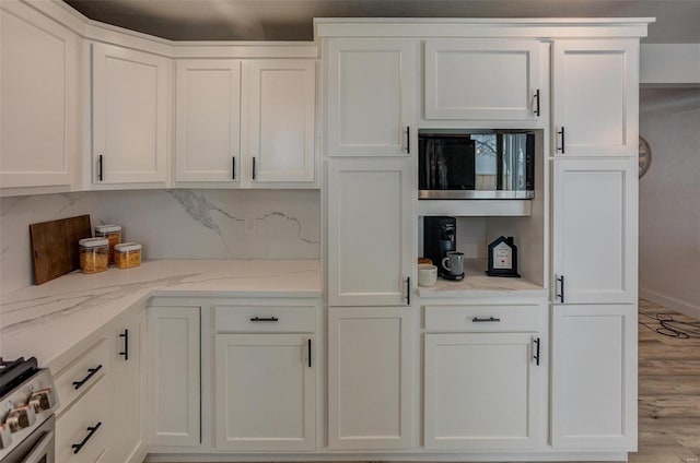 interior space with white cabinetry, light stone countertops, and light wood-type flooring