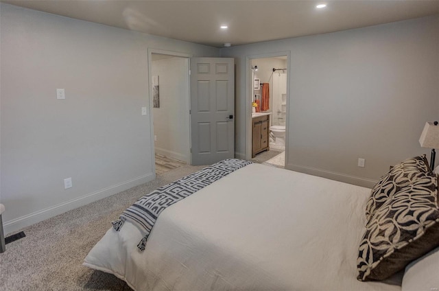 bedroom with light colored carpet and ensuite bath