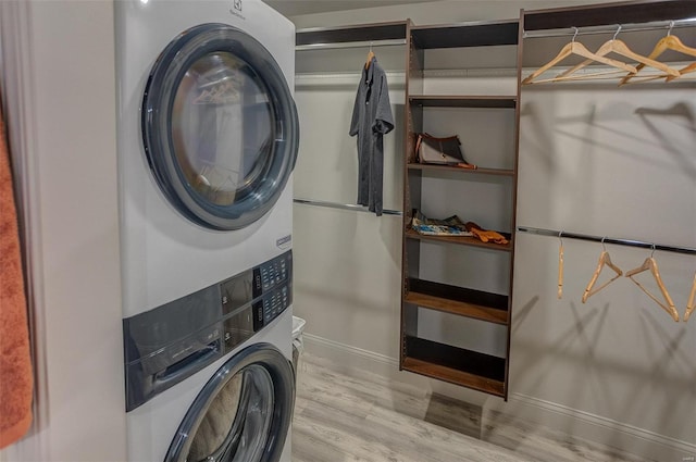 clothes washing area featuring stacked washer / drying machine and light hardwood / wood-style flooring