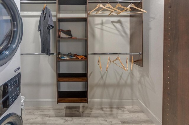 spacious closet featuring hardwood / wood-style floors and stacked washer and clothes dryer