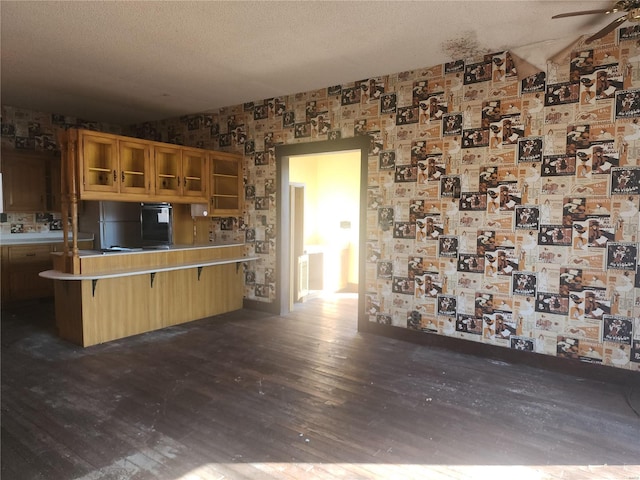 kitchen featuring a breakfast bar area, dark hardwood / wood-style flooring, ceiling fan, kitchen peninsula, and a textured ceiling