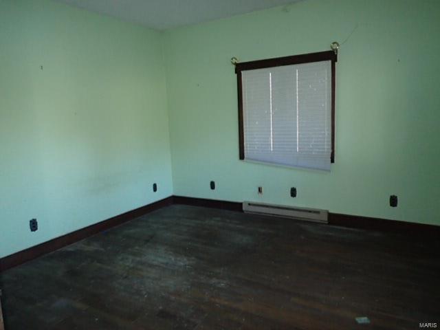 unfurnished room with dark hardwood / wood-style floors and baseboard heating