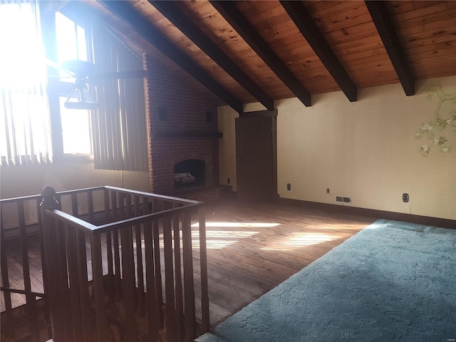 interior space featuring hardwood / wood-style flooring, vaulted ceiling with beams, wooden ceiling, and a fireplace