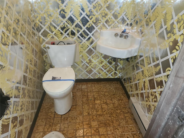 bathroom featuring sink, toilet, and baseboard heating