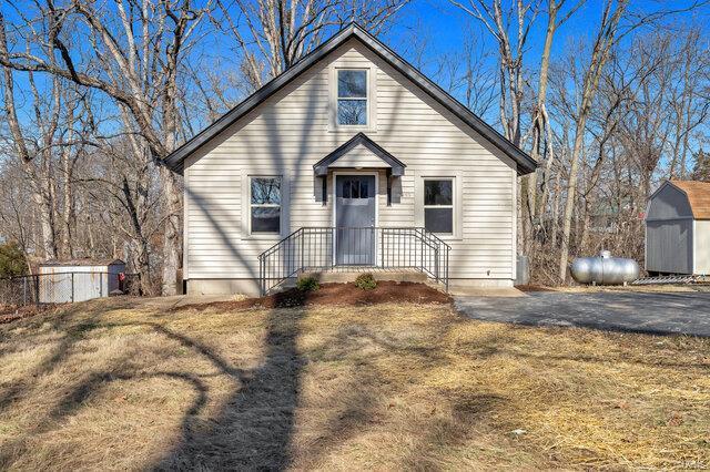 view of front of house featuring a storage unit and a front lawn