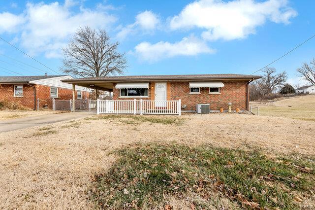 single story home with cooling unit and a front lawn