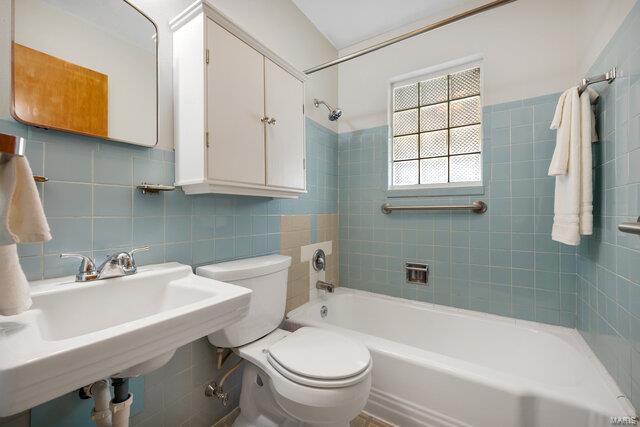 full bathroom with sink, tile walls, tiled shower / bath combo, tasteful backsplash, and toilet