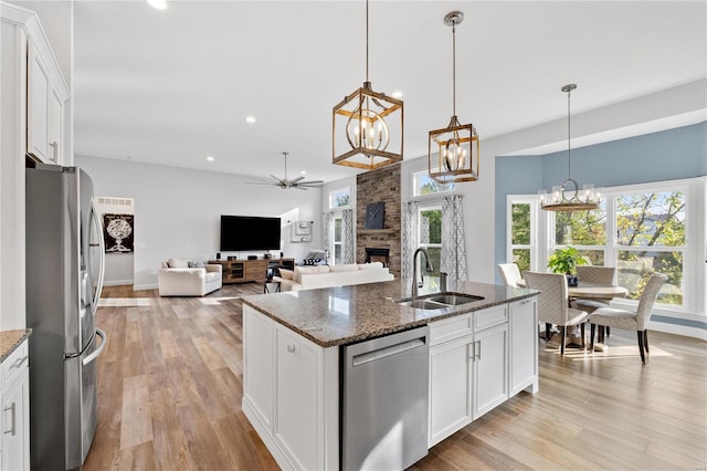 kitchen with white cabinetry, stainless steel appliances, sink, and dark stone countertops