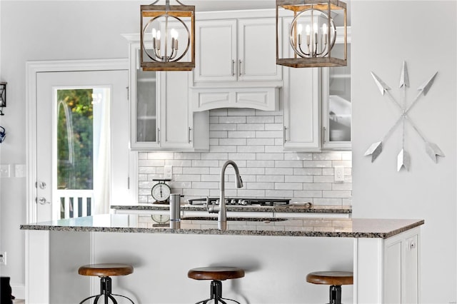 kitchen featuring white cabinetry, dark stone counters, and a breakfast bar