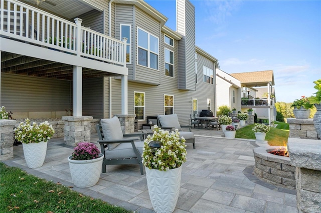 view of patio with a balcony and an outdoor fire pit