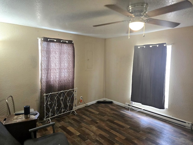 spare room with ceiling fan, a baseboard heating unit, and dark hardwood / wood-style flooring