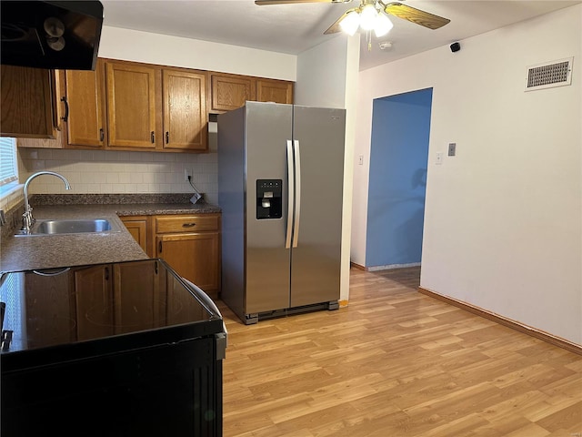 kitchen with sink, extractor fan, light hardwood / wood-style flooring, stainless steel fridge, and black range with electric cooktop