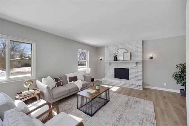 living room with light wood-type flooring, a fireplace, and baseboards