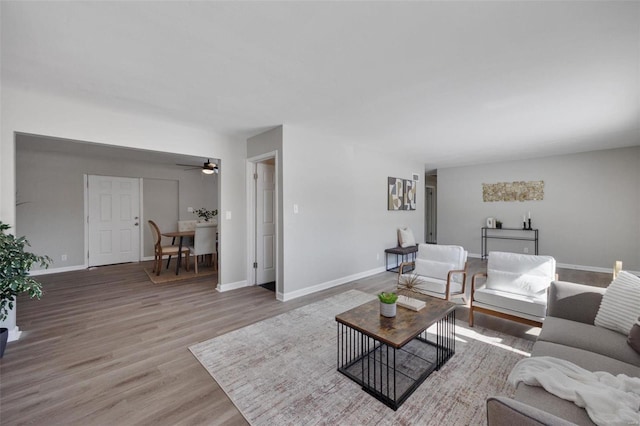 living room featuring light wood-style floors, ceiling fan, and baseboards